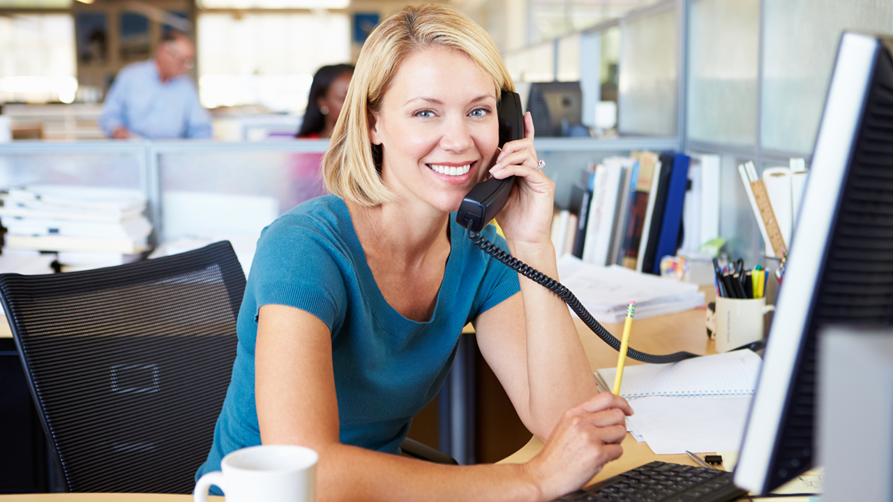 Business woman smiling and talking on the phone in an office