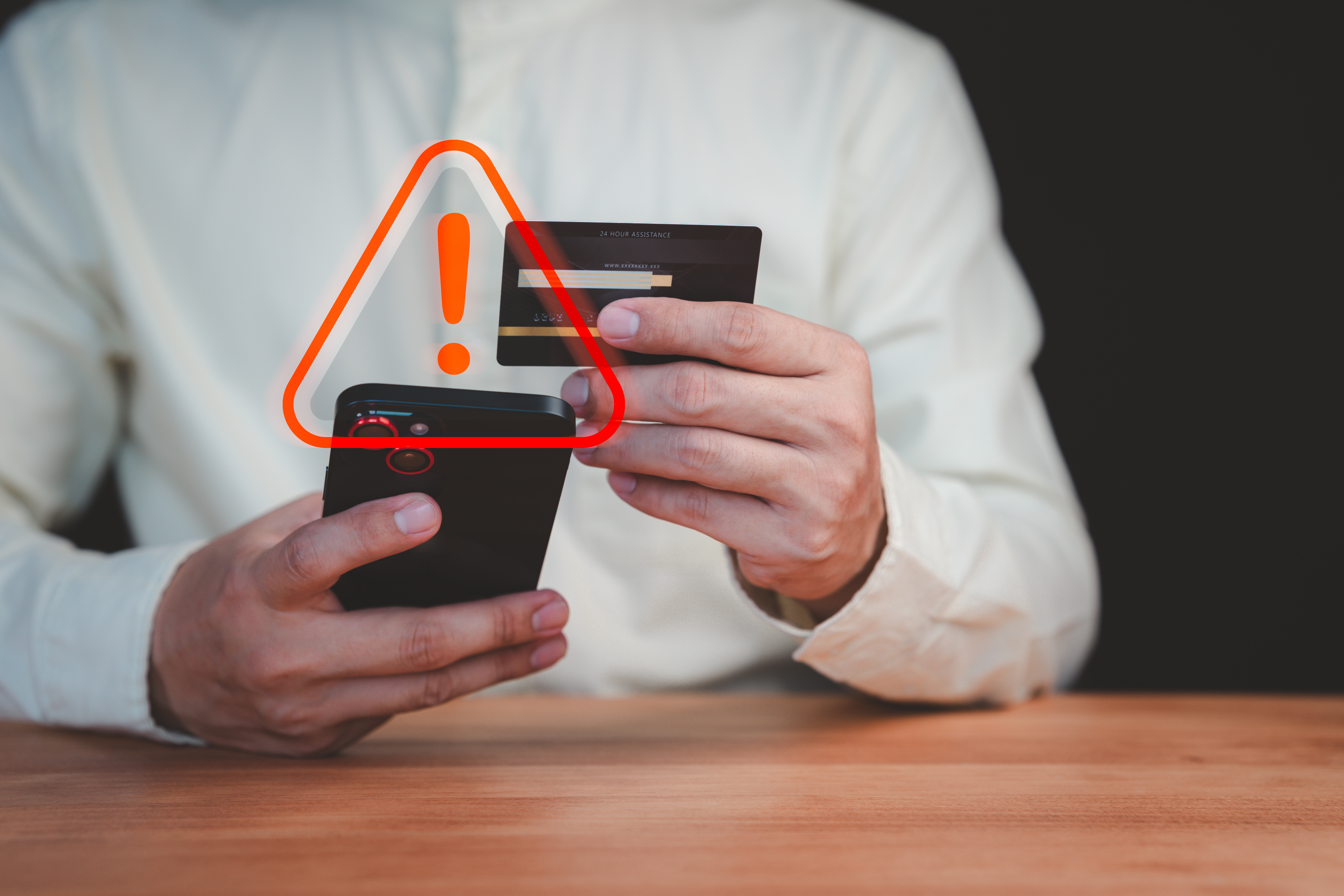 Picture of someone holding a phone and a credit card with a fraud alert